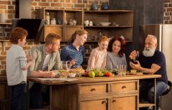 multigeneration family cooking dinner together in kitchen at home